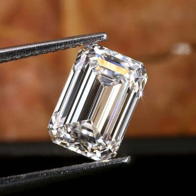Emerson cut diamond held by tweezers with a blurred background